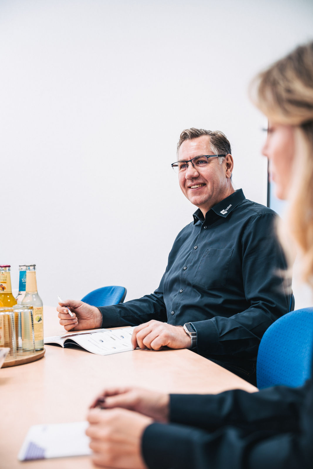Viktor Leicht von hcsystem lächelt im Beratungsgespräch am Besprechungstisch.