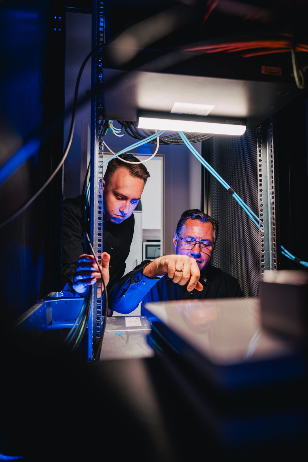 Viktor Leicht und ein Kollege von hcsystem arbeiten an einem geöffneten Serverschrank.
